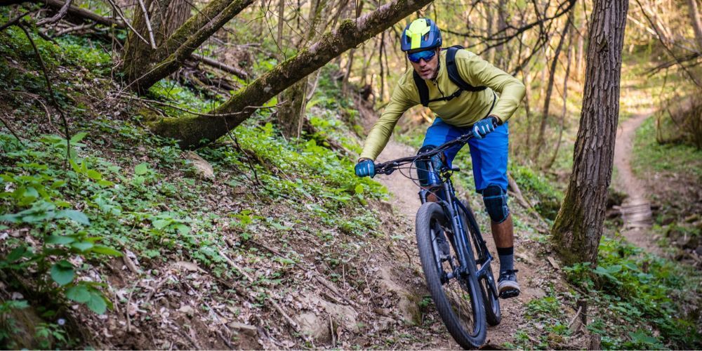 A man is riding a mountain bike down a trail in the woods.