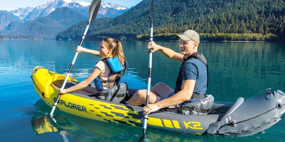 A man and a woman are paddling a kayak on a lake.