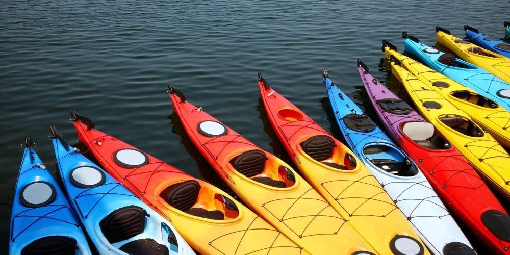 A row of colorful kayaks are lined up in the water.