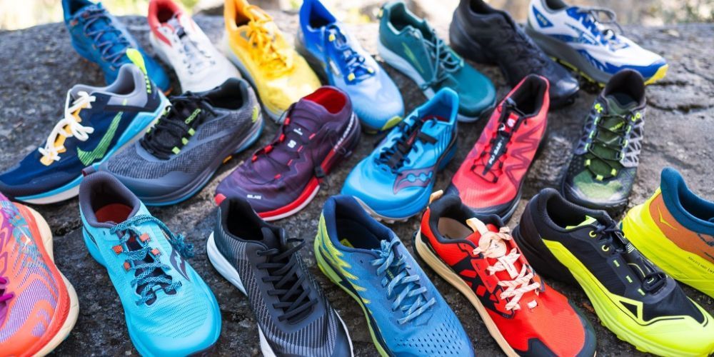 A bunch of different colored running shoes are sitting on top of a rock.