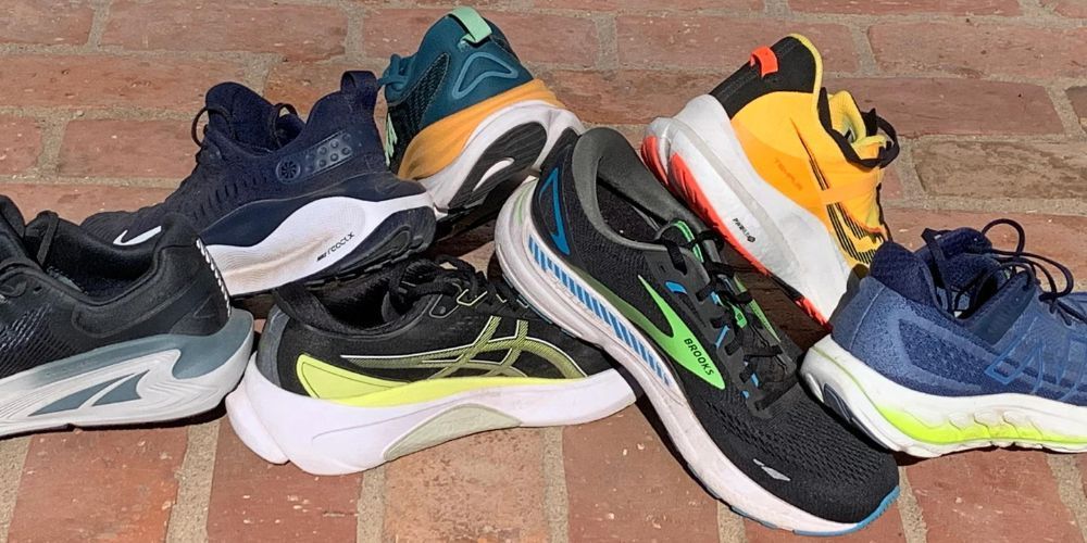 A group of running shoes are stacked on top of each other on a brick floor.