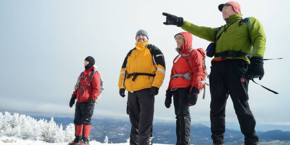 A group of people are standing on top of a snow covered mountain.