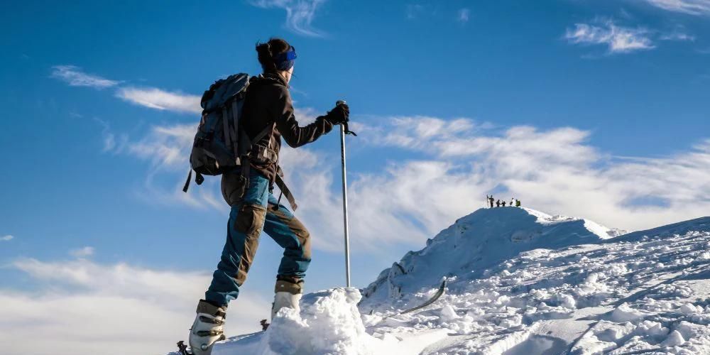 A person is standing on top of a snow covered mountain.