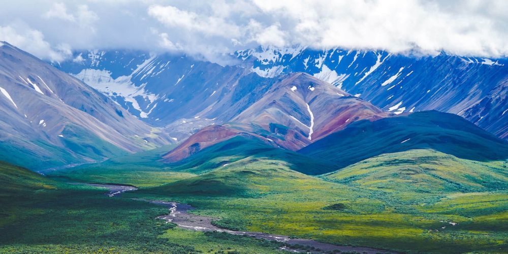 A valley with mountains in the background and a river running through it.