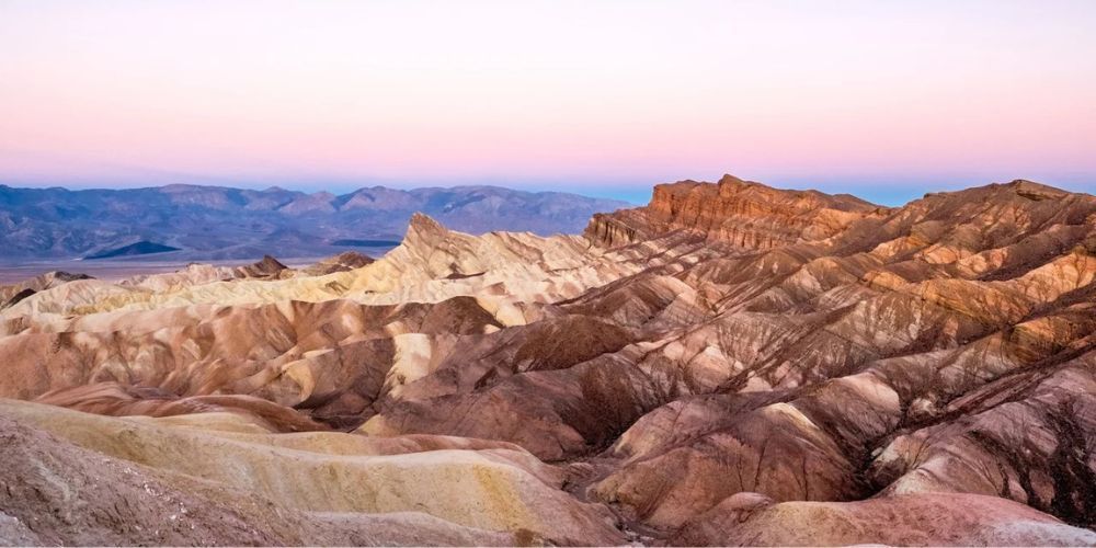 A desert landscape with mountains in the background at sunset.