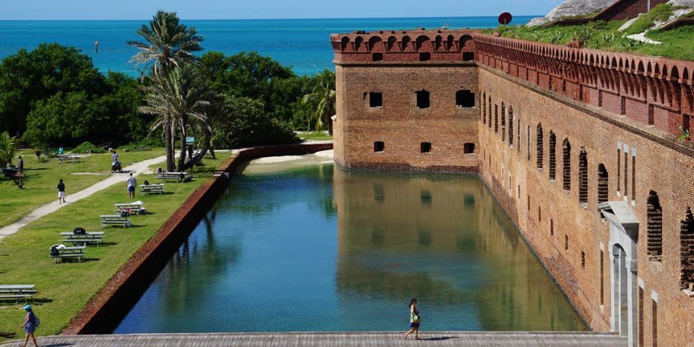 A large brick building with a large pool in front of it.