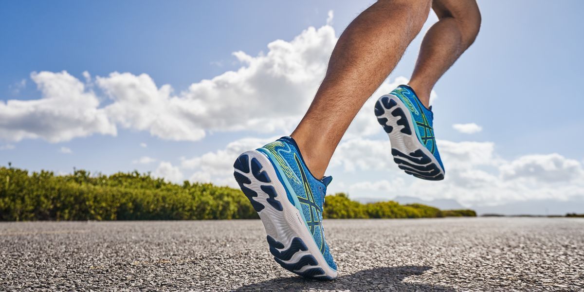 A person is running on a road wearing blue and white shoes.