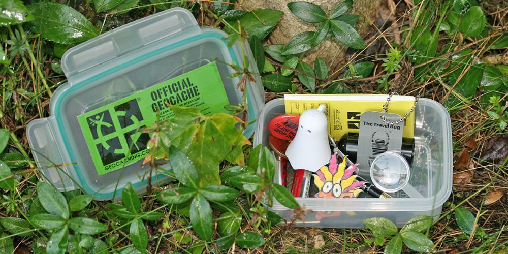 A plastic container filled with various objects is sitting in the grass.