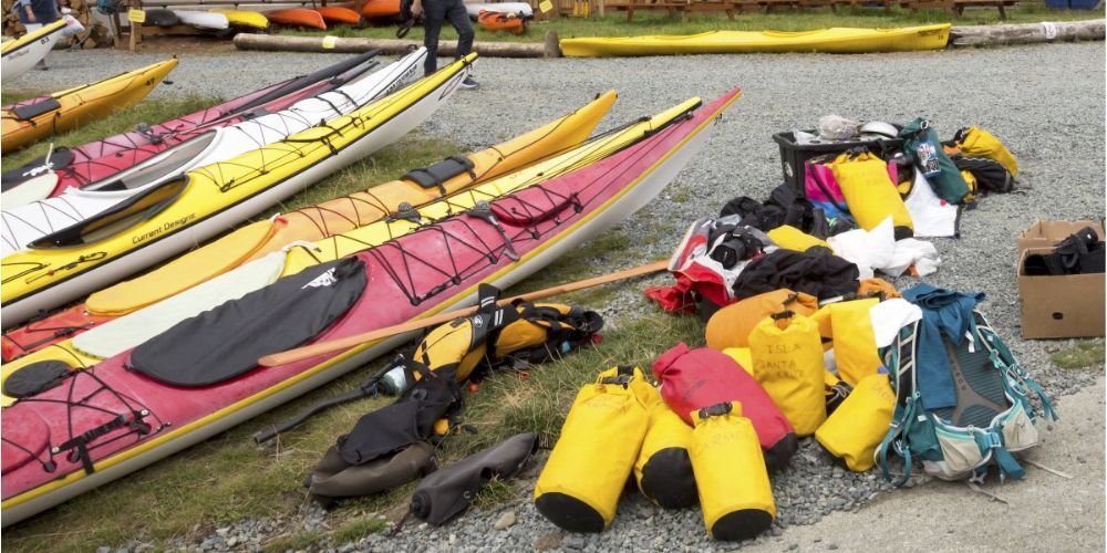 A bunch of kayaks are lined up on the ground.