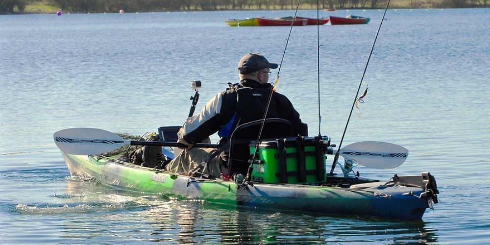 A man is fishing in a kayak on a lake