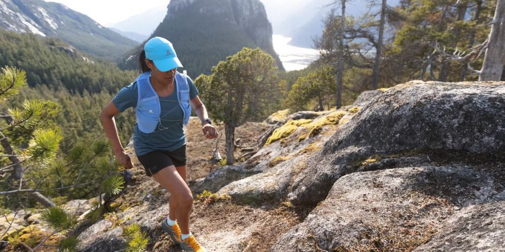 A woman is running on a trail in the mountains.