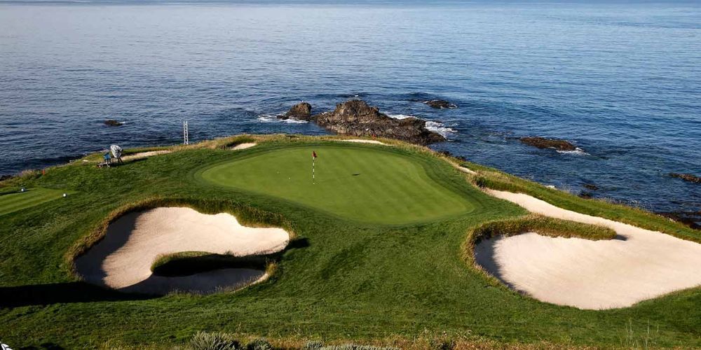 An aerial view of a golf course on a cliff overlooking the ocean.