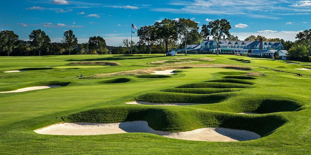 A golf course with bunkers and a house in the background.