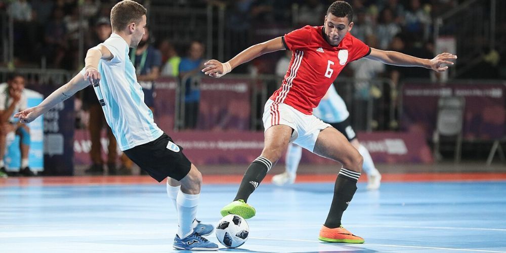 Two men are playing a game of soccer on a court.