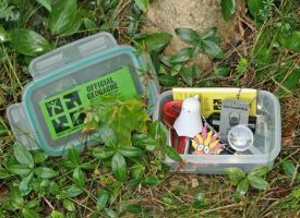 A plastic container filled with various items is sitting in the grass.