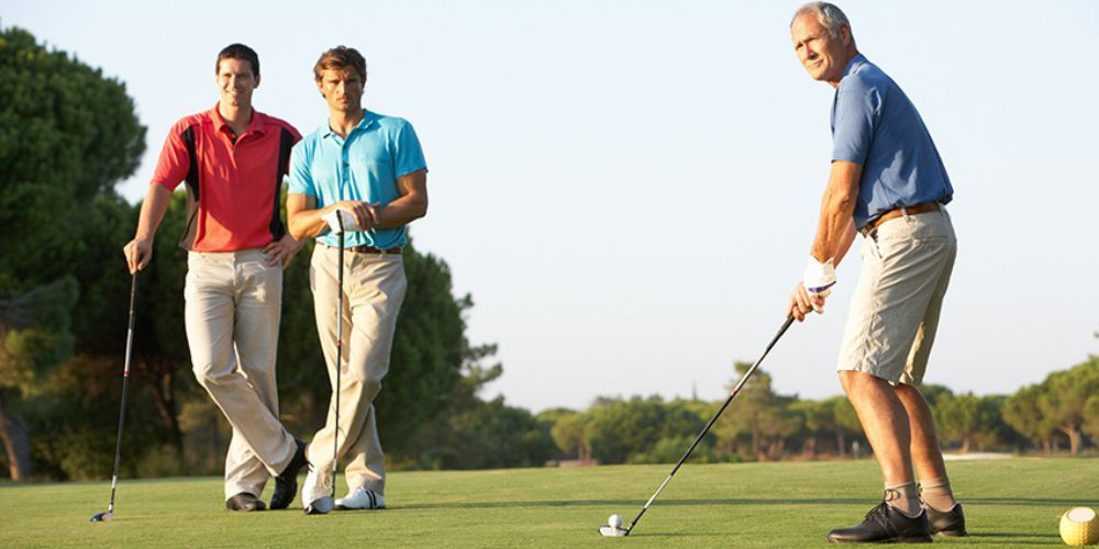 Three men are playing golf together on a golf course.