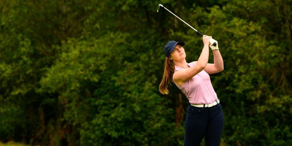 A woman is sitting in a lotus position on a golf course.
