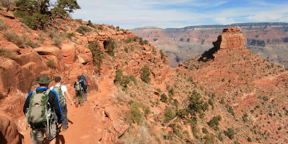 A group of people are hiking down a trail on a mountain.