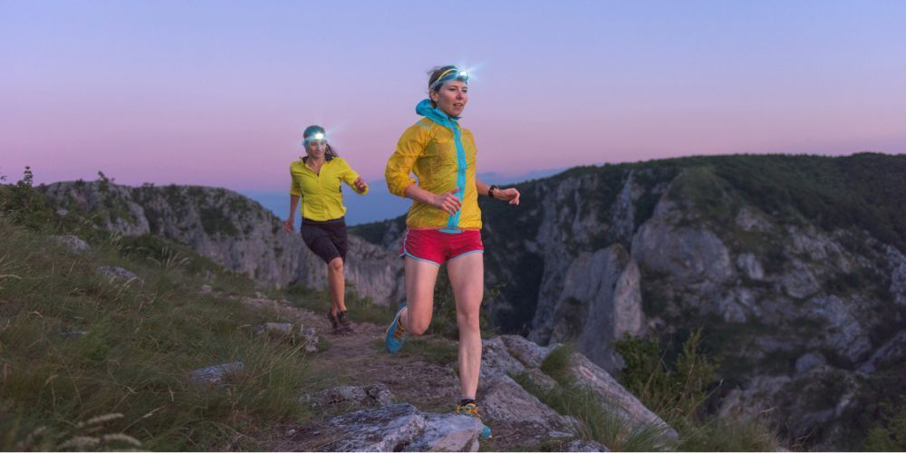 two women running at night with head lamps