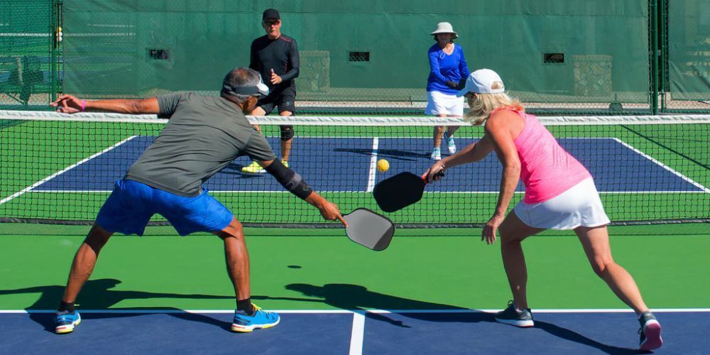 A man and a woman are playing a game of pickleball on a tennis court.