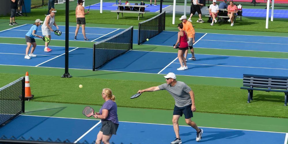 A group of people are playing pickleball on a pickleball court.