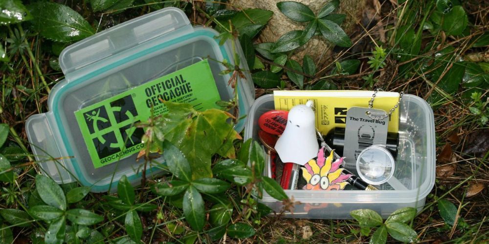 A plastic container filled with various items is sitting in the grass.