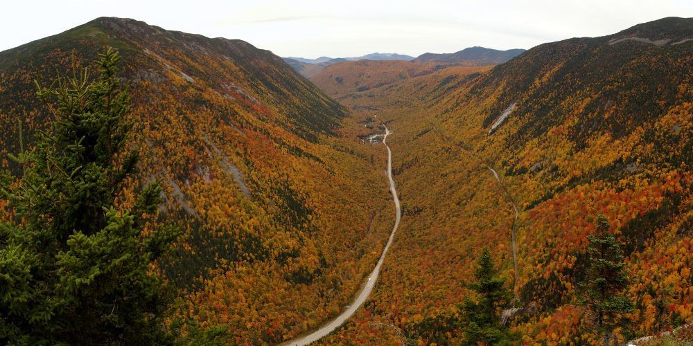 A road going through a valley surrounded by mountains in the fall.