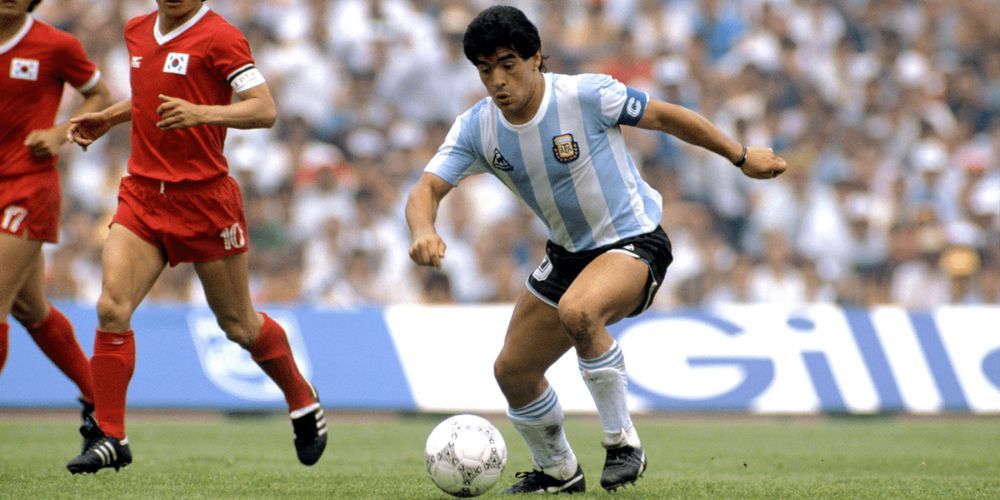 A man in a argentina jersey is dribbling a soccer ball