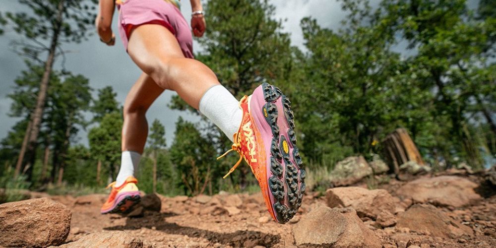 A person is running on a rocky trail in the woods.