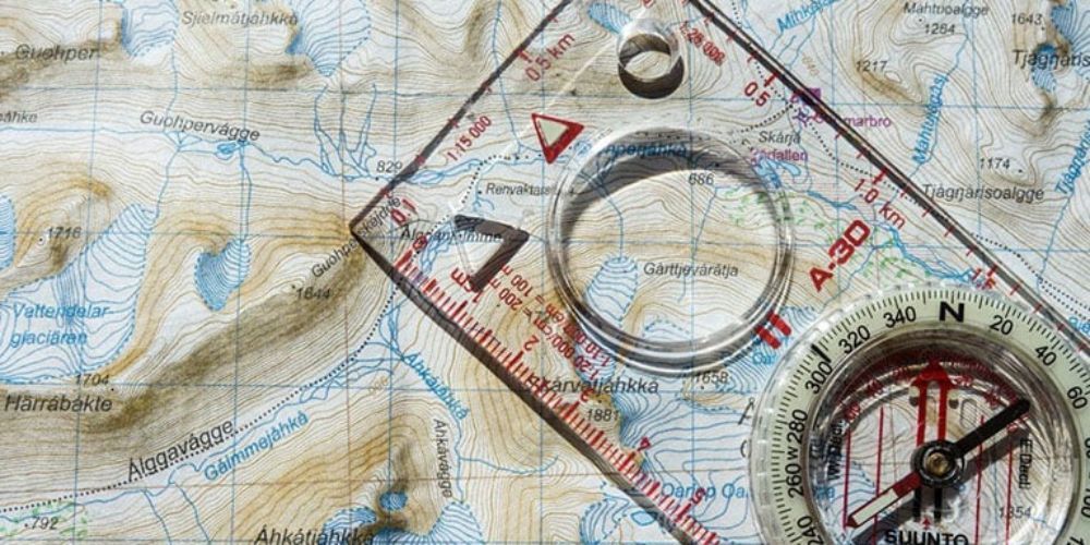 A compass and ruler are sitting on top of a map.