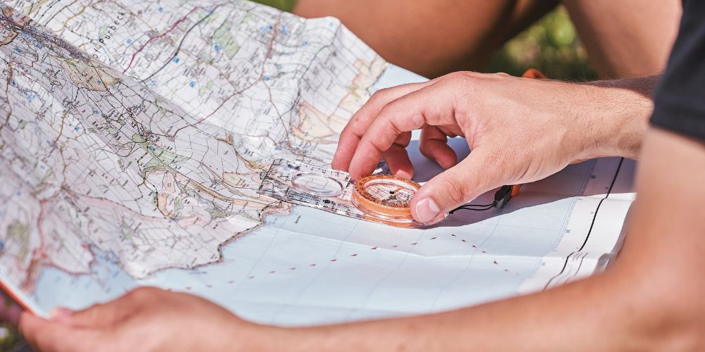 A person is holding a compass over a map.