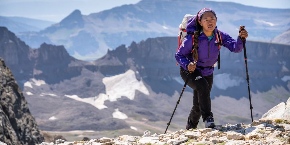 A woman with a backpack is hiking up a mountain.