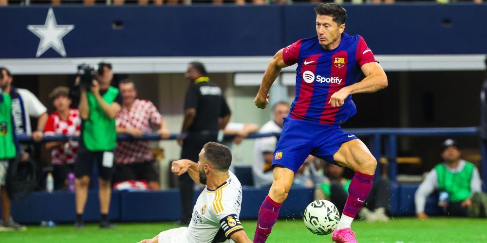 Two soccer players are playing a game of soccer on a field.