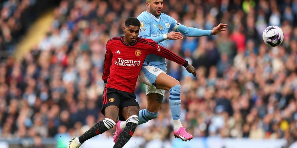 Two soccer players are playing a game of soccer on a field.