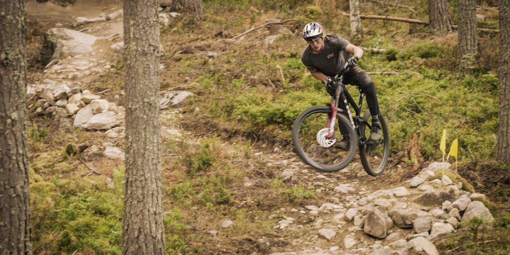 A man is riding a mountain bike down a trail in the woods.