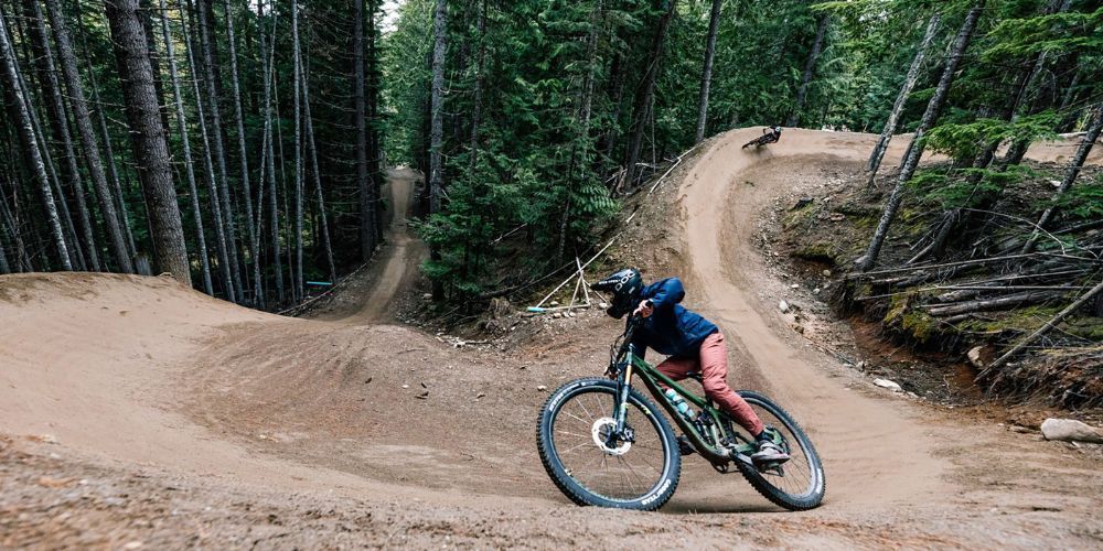 A person is riding a bike down a dirt road in the woods.