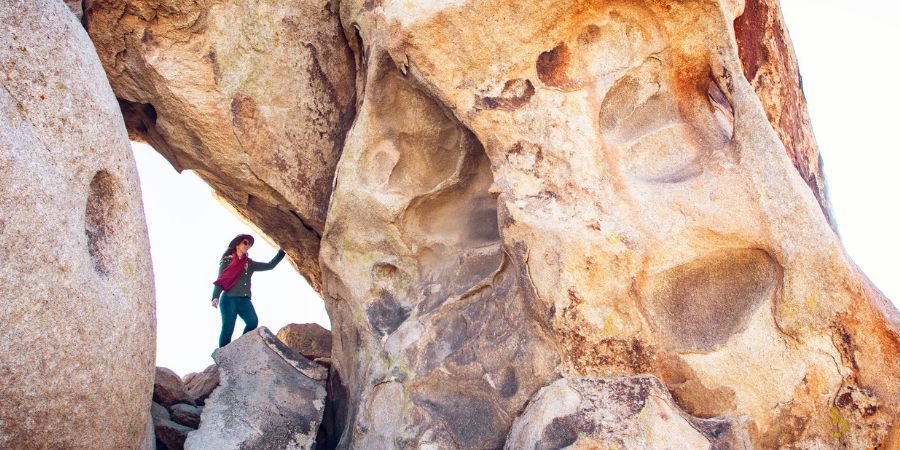 A woman is standing on top of a large rock formation.