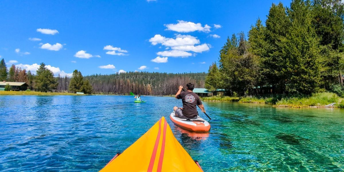 A man is paddling a yellow kayak on a lake.