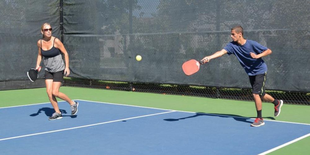 A man and a woman are playing tennis on a court.