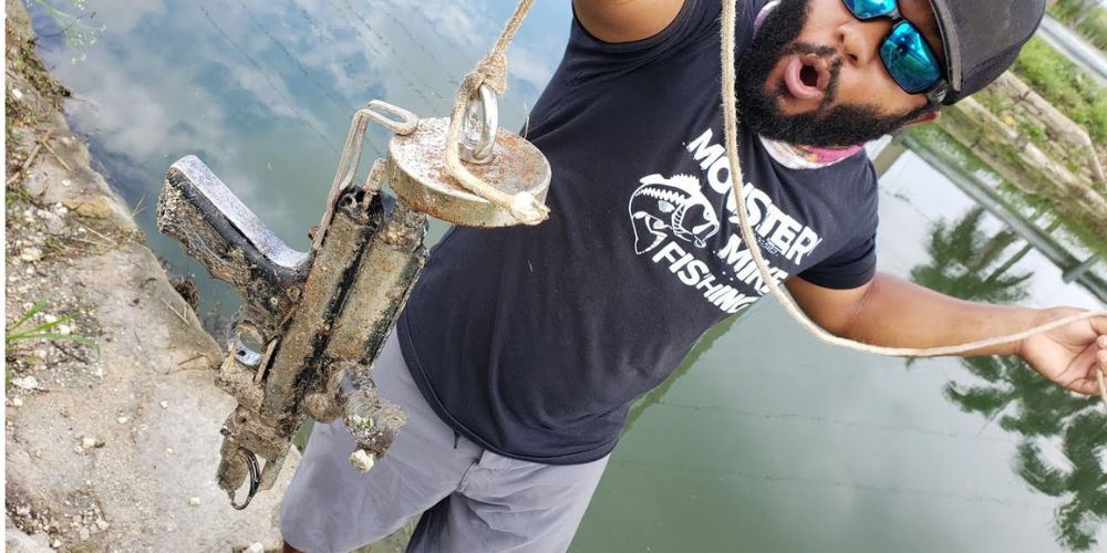 A man in a monster mike fishing shirt is holding a fishing rod.