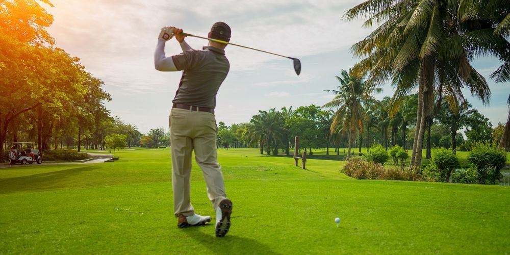 A man is swinging a golf club on a golf course.