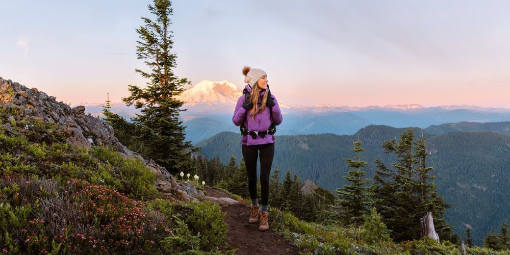 A woman is hiking on a trail in the mountains.