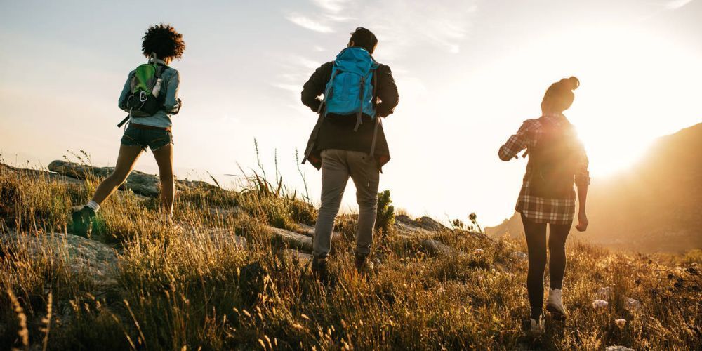 A group of people are hiking up a hill at sunset.