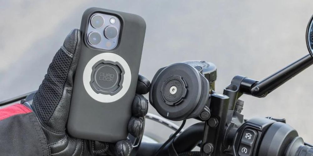 A person is holding a cell phone in their hand while riding a motorcycle.