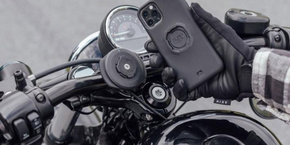 A person is holding a cell phone while riding a motorcycle.