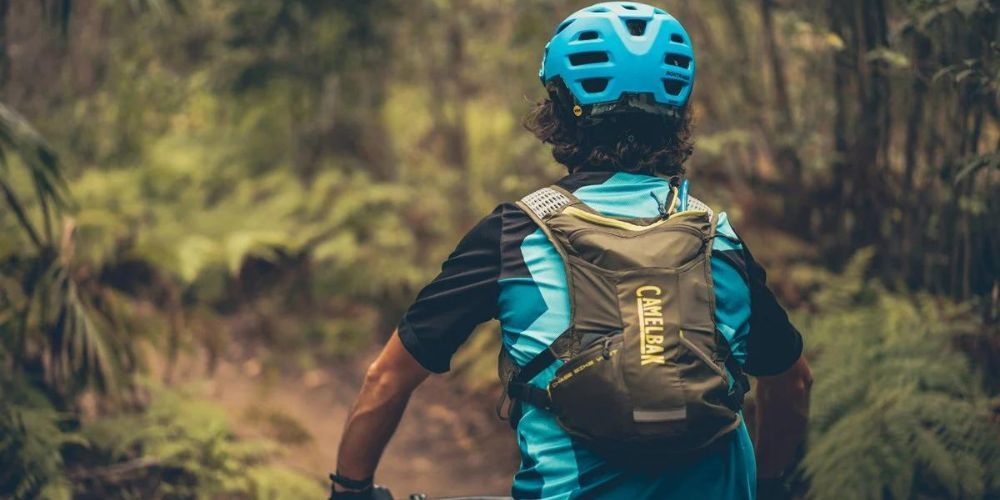 mountain biker with a hydration pack riding down a trail