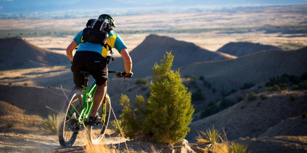 A man is riding a mountain bike down a dirt road.