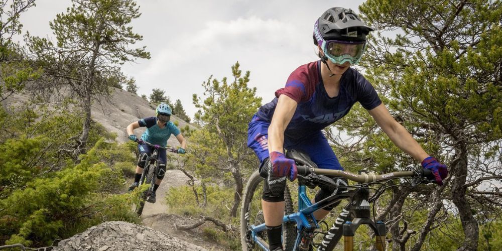 Two people are riding mountain bikes on a trail in the woods.