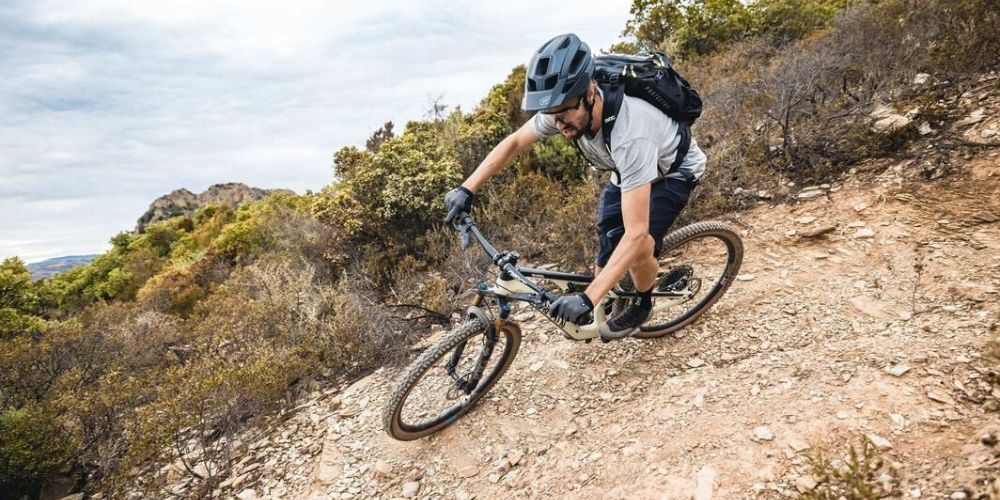 A man is riding a mountain bike down a dirt trail.