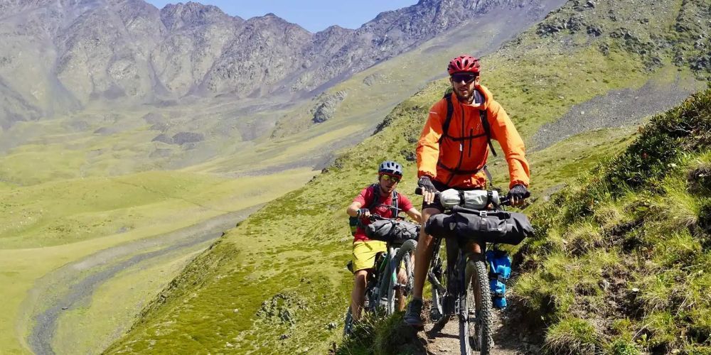 A man and a child are riding bikes on a trail in the mountains.